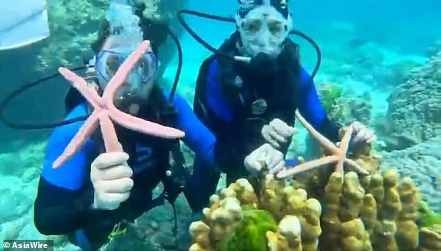 Dua dari tiga wisatawan China berfoto bersama bintang laut saat menyelam di Thailand.