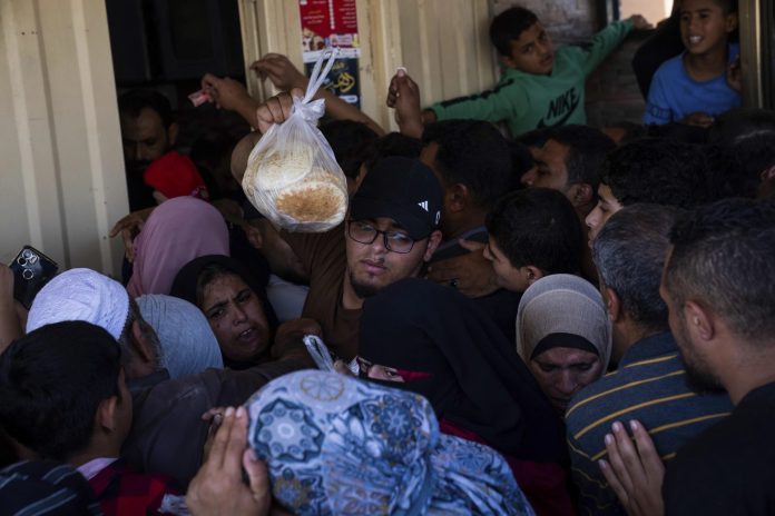 Warga Palestina berebut membeli roti dari sebuah toko di Khan Younis, Jalur Gaza pada minggu, 15 Oktober 2023 (Foto: AP/ Fatima Shbair/ THE EDITOR)
