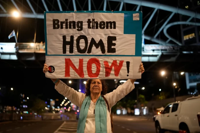 Seorang wanita memegang poster yang mendorong Pemerintah Israel untuk segera memulangkan sandera dari tahanan Hamas. (Foto: Christopher Furlong/GETTY IMAGES)