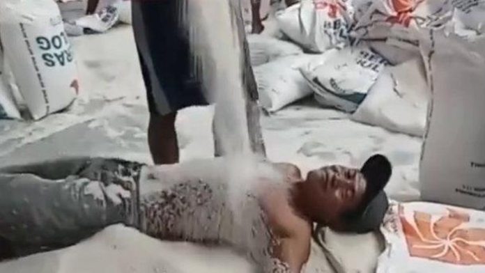 Oknum buruh Bulog melakukan ‘mandi’ beras di gudang di Surabaya, Jawa Timur. (Foto: Media sosial/THE EDITOR)