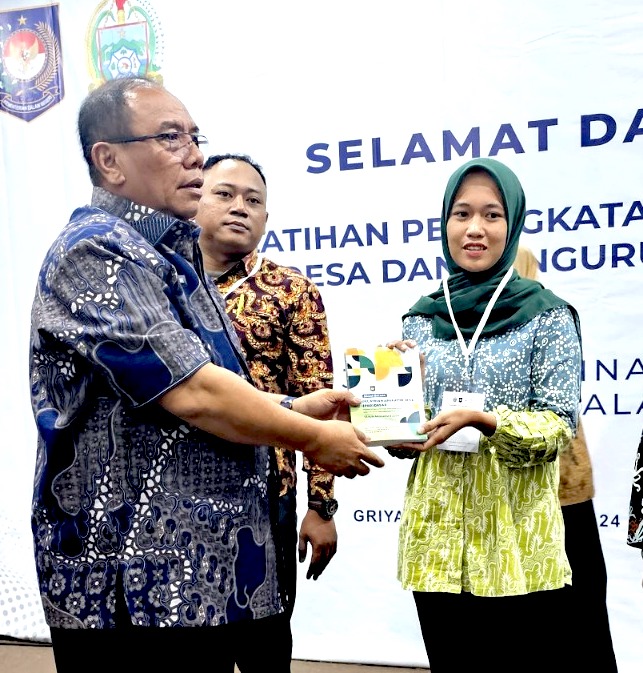 Kepala Dinas PMD Dukcapil Provinsi Sumatera Utara Parlindungan Pane menyerahkan buku pelatihan kepada peserta pelatihan di Hotel Griya Medan pada Kamis, 22 Agustus 2024 (Foto: RMC Sumatera Utara/THE EDITOR)