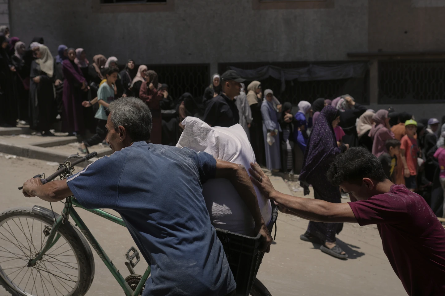 Warga Palestina membawa karung-karung berisi tepung yang didistribusikan oleh World Food Programme (WFP) di Jalur Gaza Utara, Kota Gaza pada Sabtu, 12 Juli 2025 (FOTO: The Associated Press/Jehad Alshrafi/THE EDITOR)