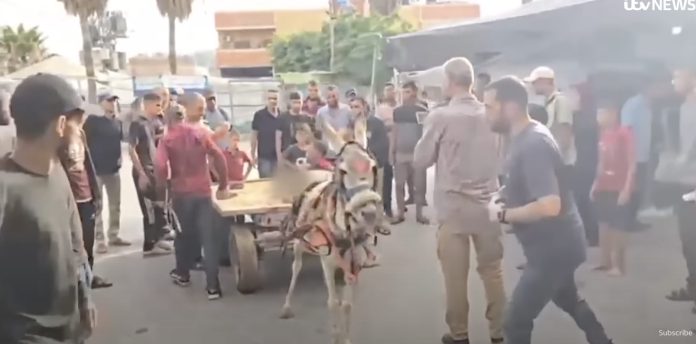 Korban tewas ditarik dengan kereta keledai dan dikerumuni oleh pria. Tayangan video ini disiarkan oleh ITV News pada 11 Juli 2025 (FOTO: Tangkapan layar YouTube ITV/THE EDITOR)