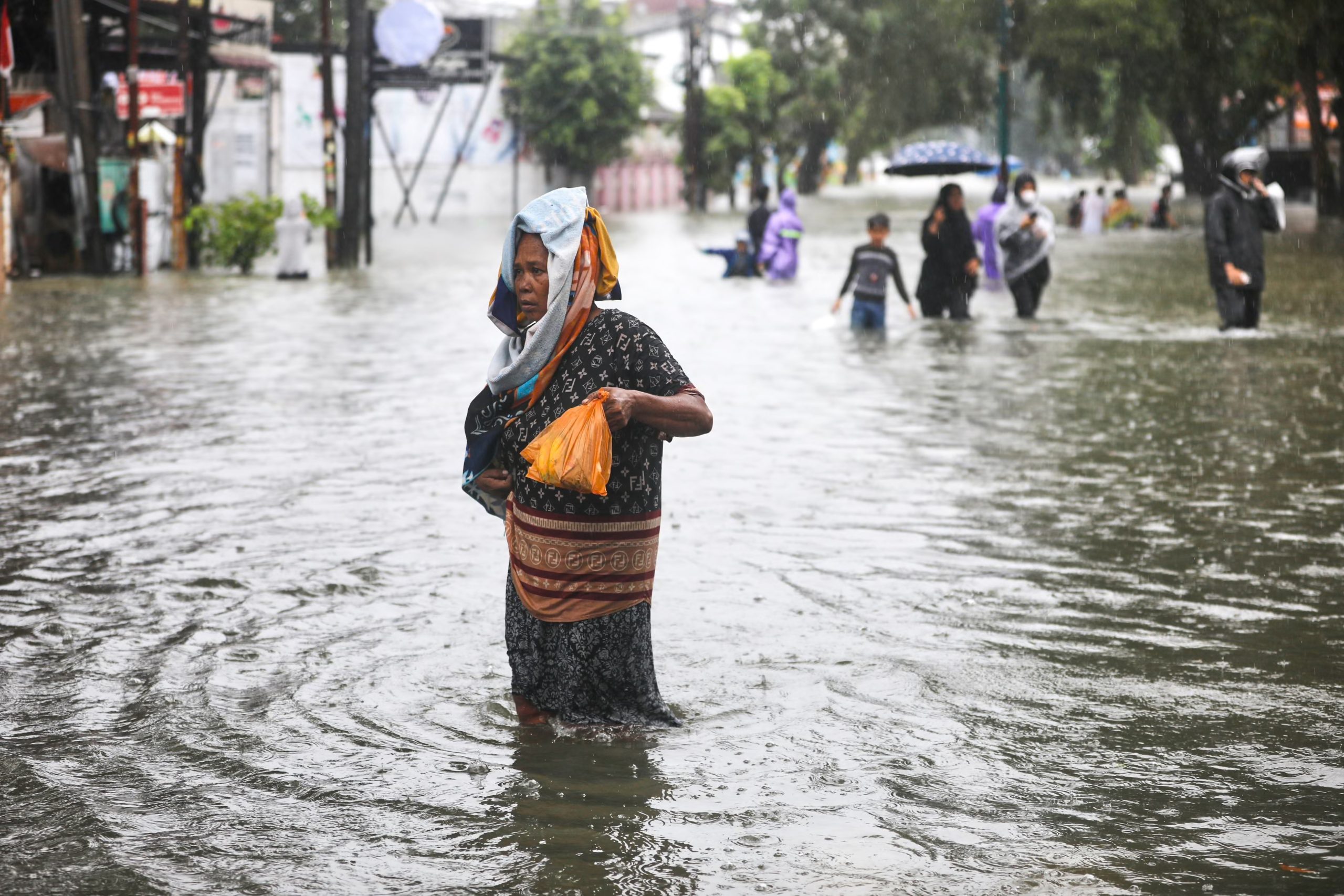 People wade through the water at a flooded street in Medan, North Sumatra, Indonesia. (PHOTO: Binsar Bakkara/AP/The Guardian/THE EDITOR)
