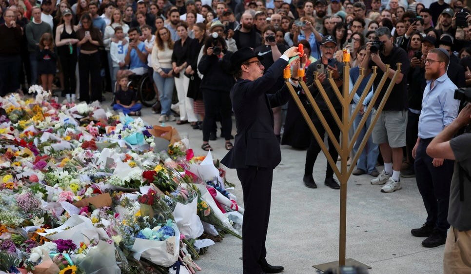 Rabbi Levi Wolff lighting a menorah at Bondi Pavilion beside a memorial for the Hanukkah massacre's victims in Sydney, Australia, earlier today. (Photo: Hollie Adams/Reuters)
