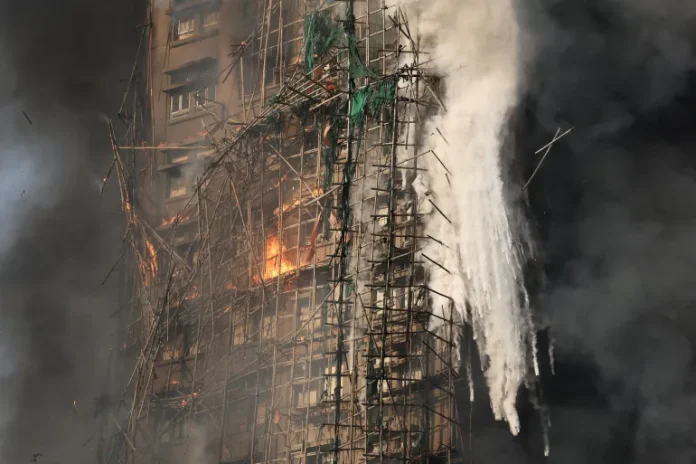 Smoke rises while flames burn bamboo scaffolding and green netting on a building at Wang Fuk Court housing estate, in Tai Po, Hong Kong, November 26, 2025 [Tyrone Siu/Reuters/Al Jazeera )