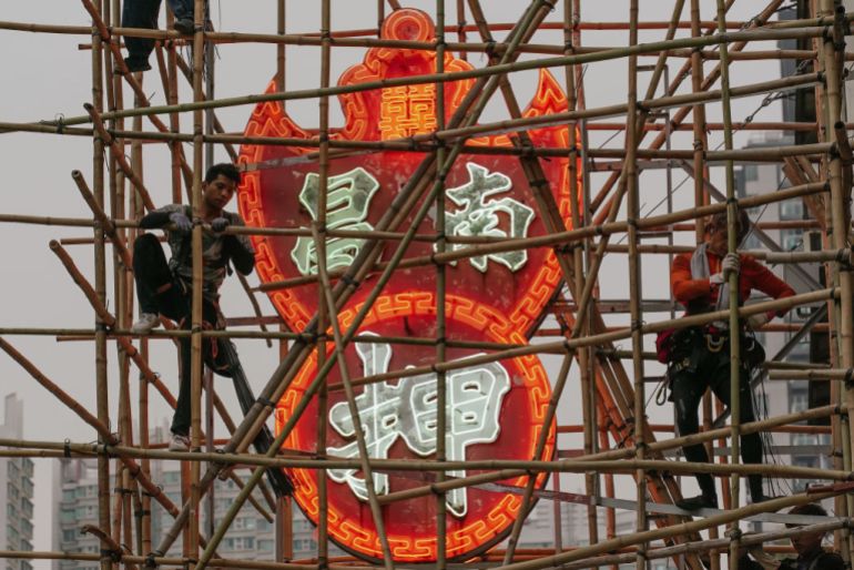 Workers set up bamboo scaffolding in preparation for removing the neon signs of a pawn shop in Sham Shui Po district in Hong Kong [File: Anthony Kwan/Getty Images/Al Jazeera )