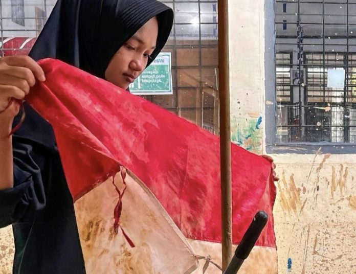 Media Vatikan mengunggah foto seorang wanita korban banjir terlihat tengah menyelamatkan bendera kebangsaan Indonesia yang berwarna merah dan putih dari banjir (Foto: Instagram @vaticannewspt)