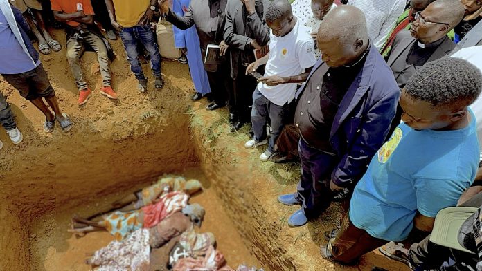 Pada tanggal 13 Jul 2026 terlihat Pendeta Ezekiel Dachomo, kedua dari kanan, memandangi jenazah sembilan anggota keluarga besarnya yang tewas dalam serangan malam hari pada tanggal 12 Juli di Kum, dekat Jos. Kum adalah sebuah desa atau komunitas pedesaan kecil yang terletak di wilayah Riyom, Negara Bagian Plateau, Nigeria Tengah. (Foto sengaja disamarkan demi menghormati privasi korban dan keluarga/TruthNigeria.Com).